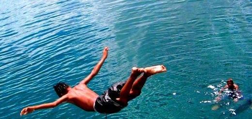 Person Cliff Diving Into deep blue waters.